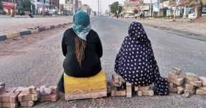 Two Sudanese women sit on a brick barricade in the capital Khartoum.