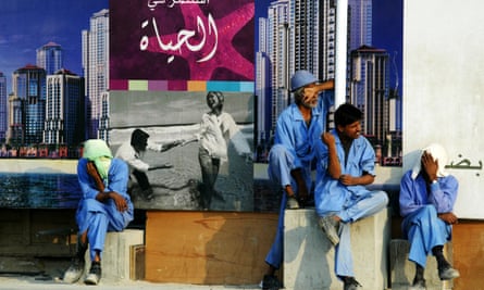 Exhausted Indian labourers sit under a real-estate advertising poster that reads: ‘Invest in life’, in Dubai in 2005.