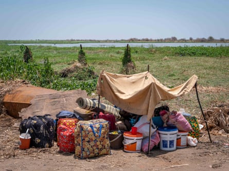Una mujer descansa bajo el refugio que construyó con una sábana para protegerse del sol, cerca del puerto de Renk en el Nilo Blanco.  Al igual que miles de sudaneses del sur, está esperando abordar un barco a Malakal después de huir de los combates en Jartum.