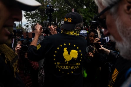 A man wearing a garment that says ‘Proud Boys’ speaks to group holding cameras successful his direction