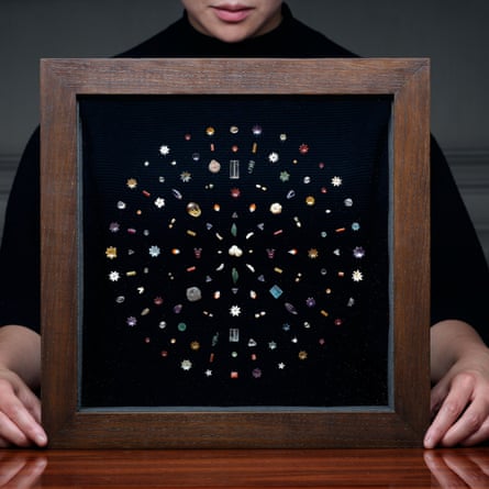 A square framed presentation box holds a circle of gems