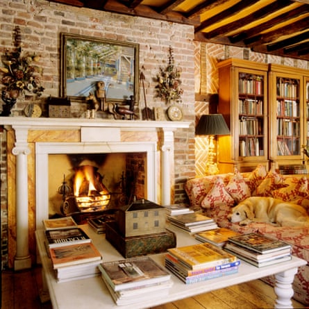 Plush, cosy room with coffee table piled with large books, fireplace in the background.