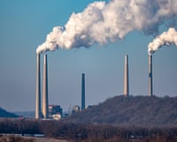 Pollution and steam rise from five towering concrete stacks .