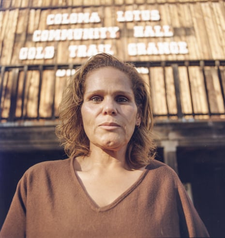 A woman stands for a portrait in front of a building with vertical wood siding.