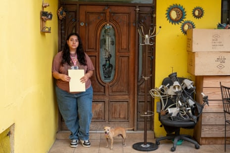 A young woman and a dog outside a house.