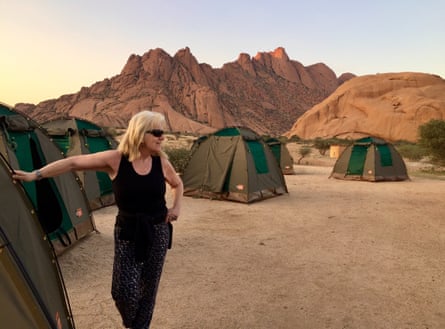 Linda standing next to a tent in a rocky desert environment.