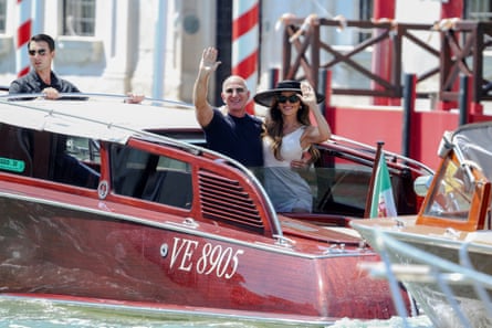 Jeff Bezos and Lauren Sánchez Bezos waving from a red boat