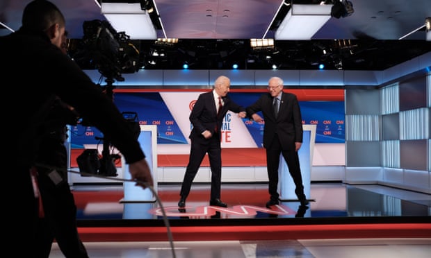 Joe Biden and Bernie Sanders greet each other with their elbows at the last Democratic presidential debate, in Washington. Sanders has been forced to cancel the rallies that are a pillar of his campaign.
