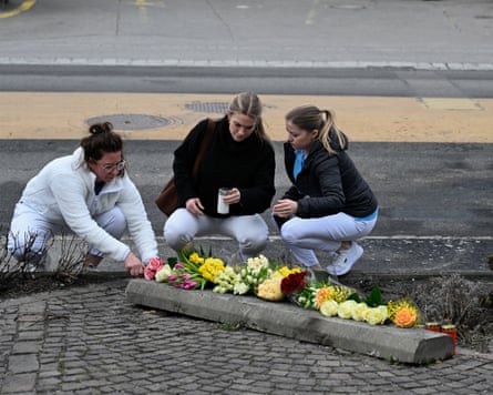 Three women crouch in front of a row of flowers on the ground