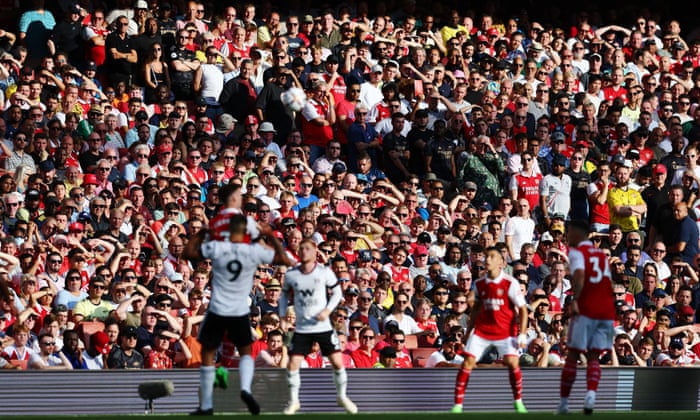Arsenal fans watch in the stands on a sunny day at the Emirates.