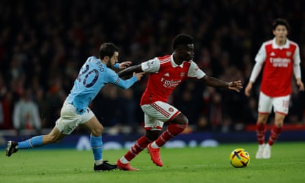 Arsenal’s Bukayo Saka runs with the ball while under pressure from Bernardo Silva of Manchester City.