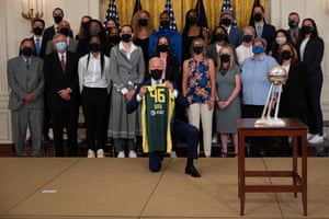 Joe Biden holds a jersey as he poses with Seattle Storm players during an event at the White House.