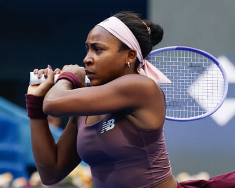 Coco Gauff, in a pink headband, with her racket behind her head after playing a shot