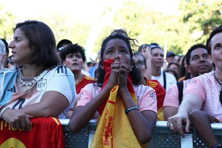 Spain fans in Madrid looking anxious, one clutching a flag