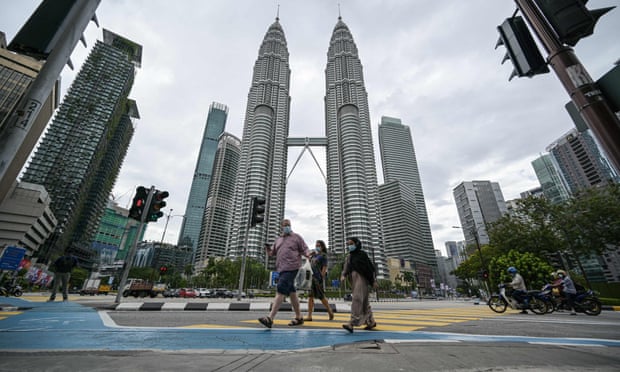 people walk in front of malaysia's petronas towers