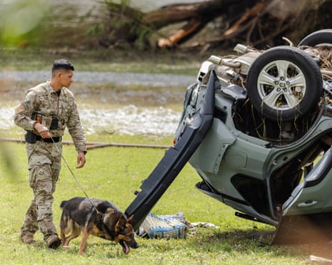 A search and rescue worker has his dog sniff through debris in Hunt, Texas.