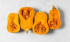 Halved butter pumpkins with seeds intact on a light grey background