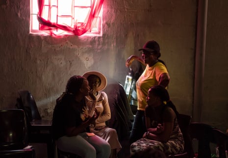 Four African women talk in a dimly lit communal area