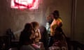 Four African women talk in a dimly lit communal area
