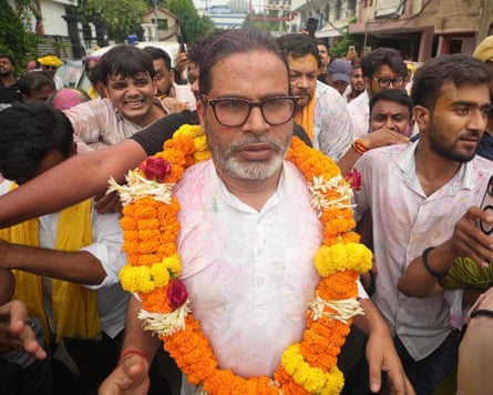 Prashant Kishor wearing a garland and surrounded by supporters in the street