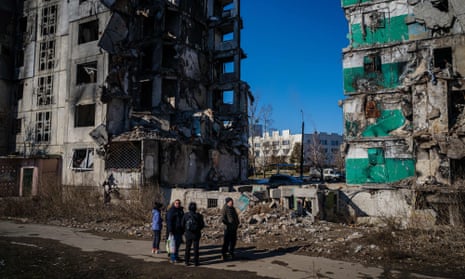 Ukrainians stand by residential buildings that were destroyed during an attack