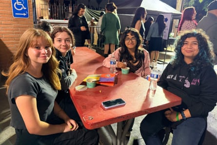 four girls smile together while seated at a table