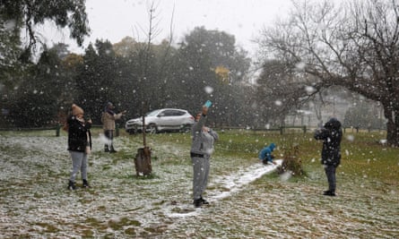 People take photos as snow falls in Zoo Lake park in Johannesburg