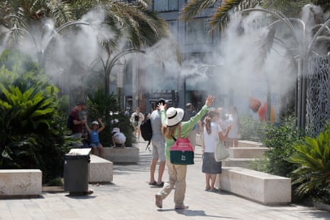 Tourists cool off under a cloud of mist at the Plaza de la Reina during a heat wave in Valencia, Spain.
