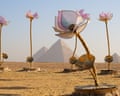 Seven large flower sculptures are seen in front of the pyramids of Giza