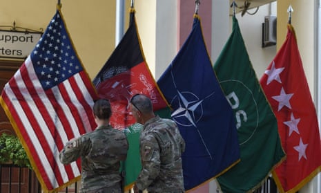 US military personnel adjust US and Afghan national flags in Kabul.