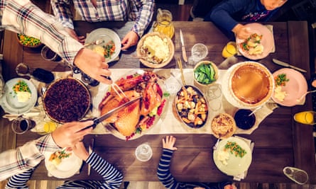 A family having a traditional holiday dinner with stuffed turkey, mashed potatoes, cranberry sauce, vegetables, pumpkin and pecan pie