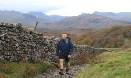 Harrison Ward hiking up Black Fell with Bowfell, Langdale Pikes and Lingmoor Fell in background.