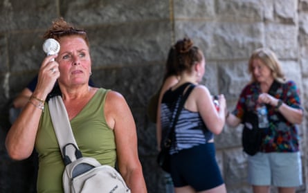 A woman uses a fan to cool off