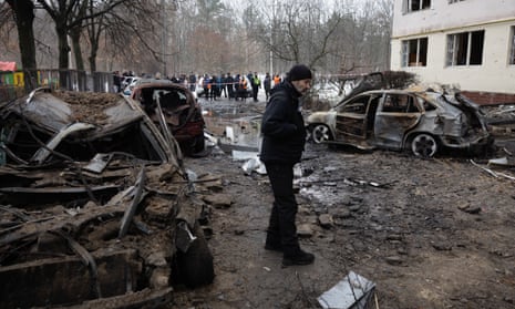A man walks amid wrecked cars lying near a residential building in Dniprovskyi district of Kyiv after a missile explosion.