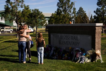 people standing by a makeshift memorial near a sign