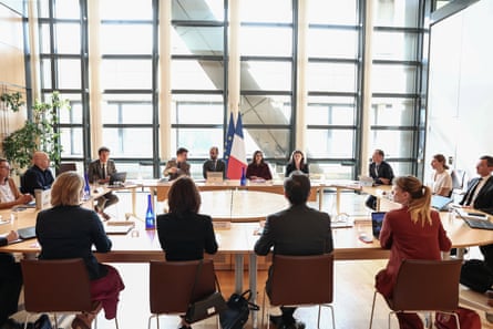 Group of people round table with French flag at back