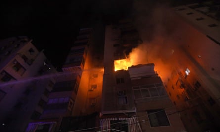 Firefighters tackle a blaze at an apartment block: it is dark and the flames are high and strong. 