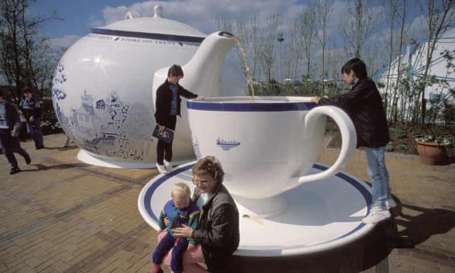 A mother and child sit on the saucer of a sculpture of a giant cup, with a giant teapot in the background – one of hundreds of attractions at the festival.