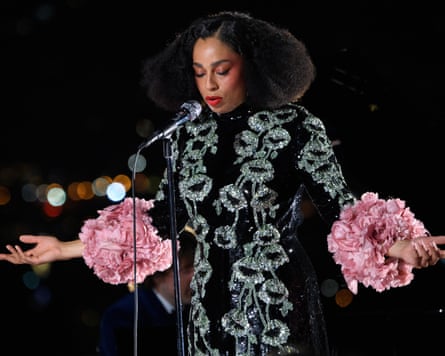 Celeste stands at the microphone with her arms out at a 45-degree angle, wearing a black dress with giant pink floral sleeves
