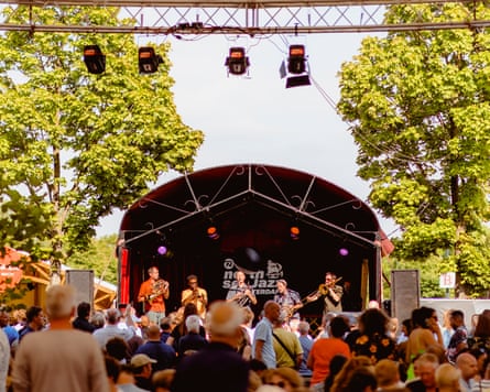 A small stage between two trees with musicians on it.