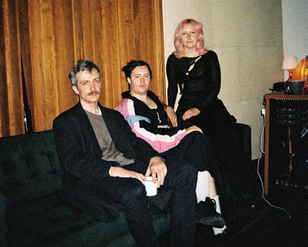The Irish band M(h)aol sit together in front of a timber wall.