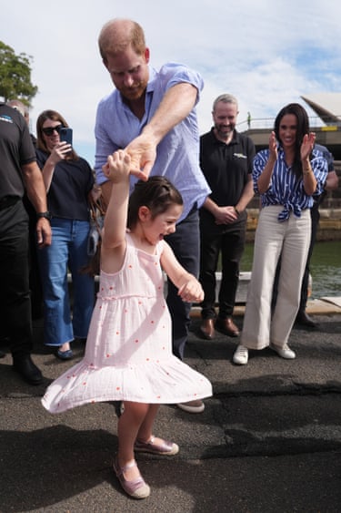 Harry twirls Charlotte, the daughter of veteran Joel Vanderzwan, at a sailing event with members of Invictus Australia in Sydney Harbour