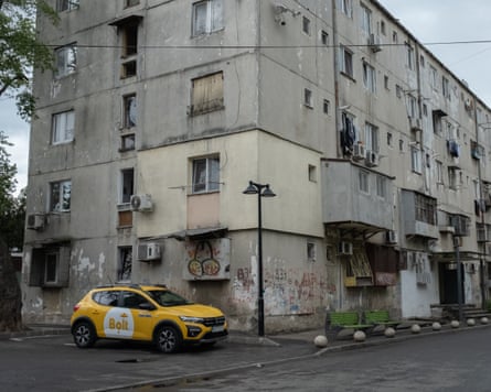 A dilapidated apartment block with a yellow car parked in front