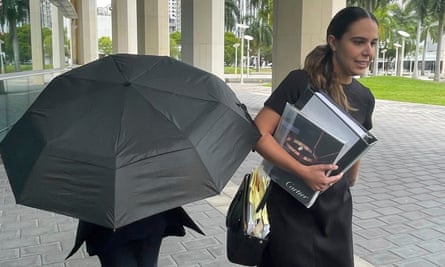 Celebrity handbag designer Nancy Gonzalez hides under an umbrella as she walks with her lawyer Andrea Lopez outside the federal courthouse in Miami on Monday.
