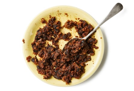 Christmas pudding broken up into pieces, with a spoon on a plate