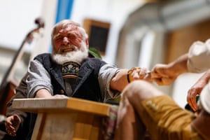 An elderly man with a white beard grimaces as he locks fingers with his opponent