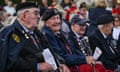 Crowd of British veterans huddle together to watch a ceremony