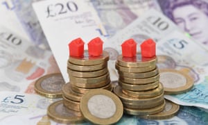 Model houses on a pile of coins and bank notes