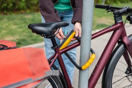A Woman Securing Bicycle with U-Lock on a City Street