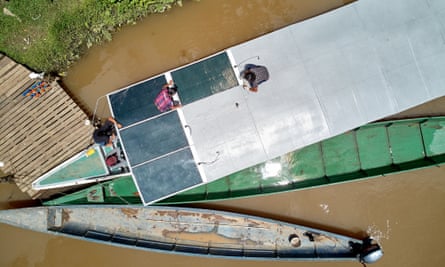 A team of indigenous technicians installs solar panels on the roof of a new canoe